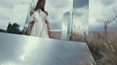 a woman in a white dress standing in front of a mirror