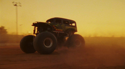 a monster truck driving down a dirt road