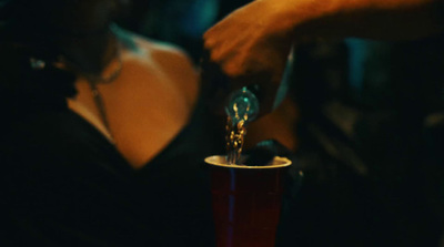 a person pouring a drink into a red cup