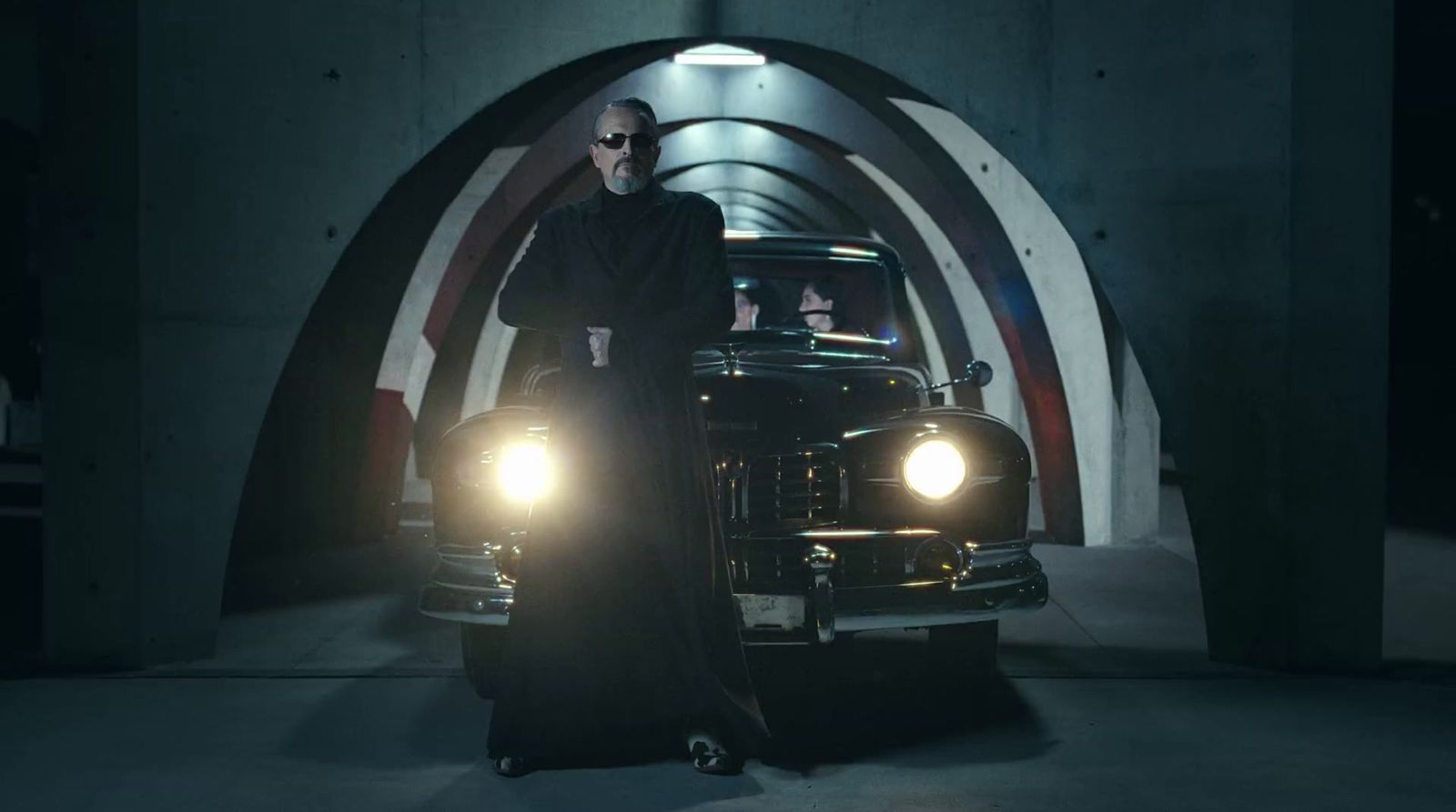 a man standing next to a car in a tunnel