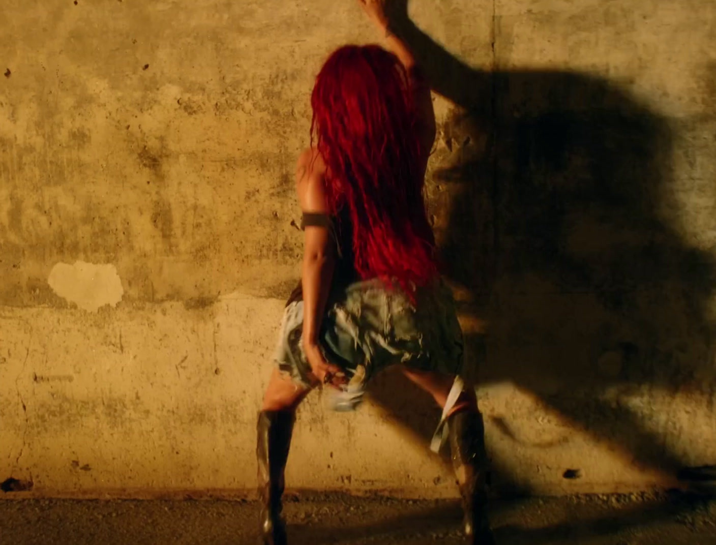 a woman with red hair leaning against a wall