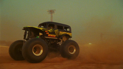 a monster truck driving down a dirt road