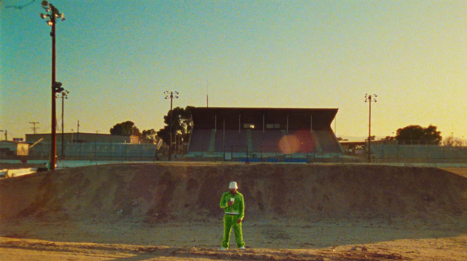 a man in a green suit standing in front of a dirt mound