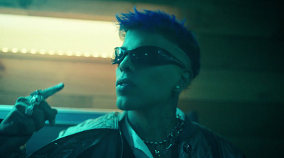 a man with blue hair and sunglasses smoking a cigarette