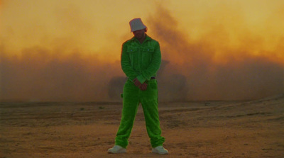 a man in a green jumpsuit standing in front of a dust storm