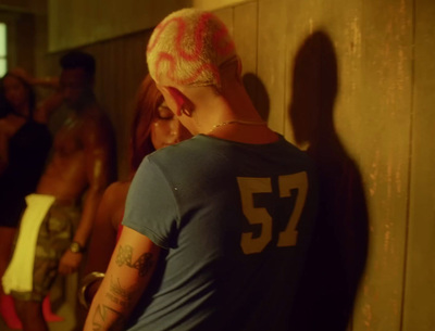 a man with pink hair standing next to a wall