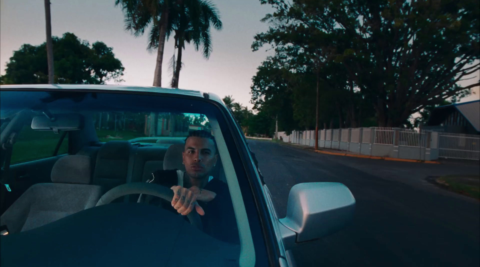 a man sitting in a car with his hand on the steering wheel