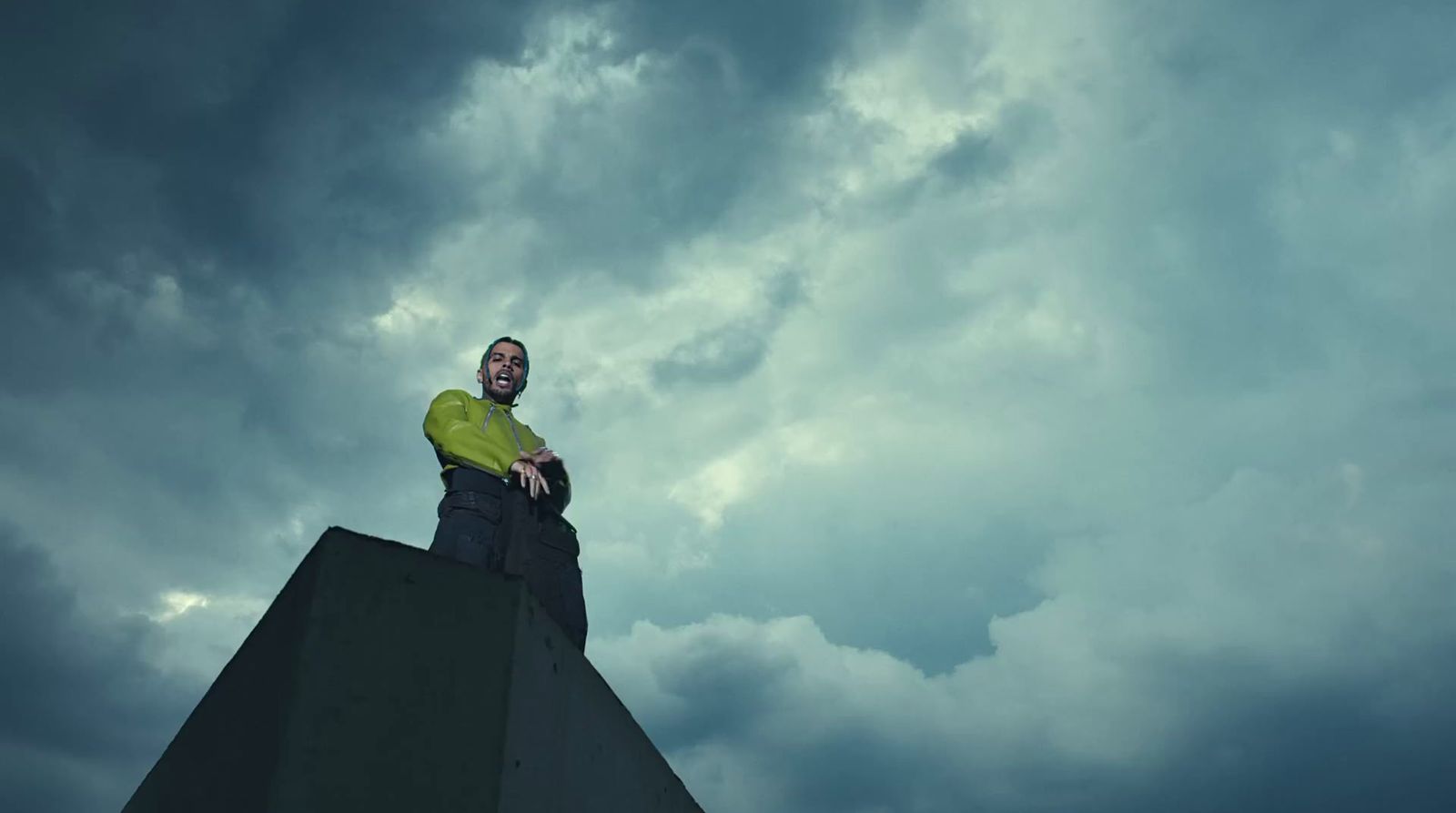 a man standing on top of a cement structure under a cloudy sky