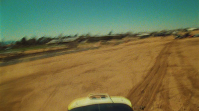 a car driving down a dirt road next to a forest