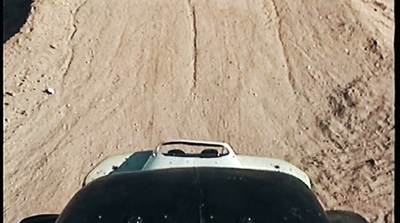 a car driving down a dirt road next to a forest