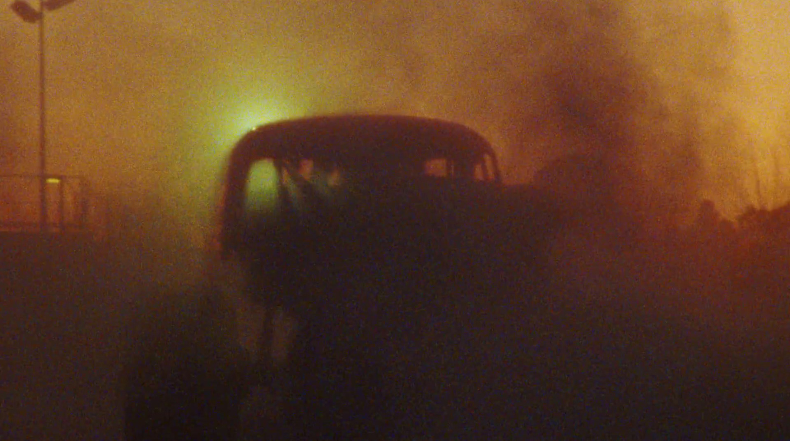 a bus driving down a foggy street at night