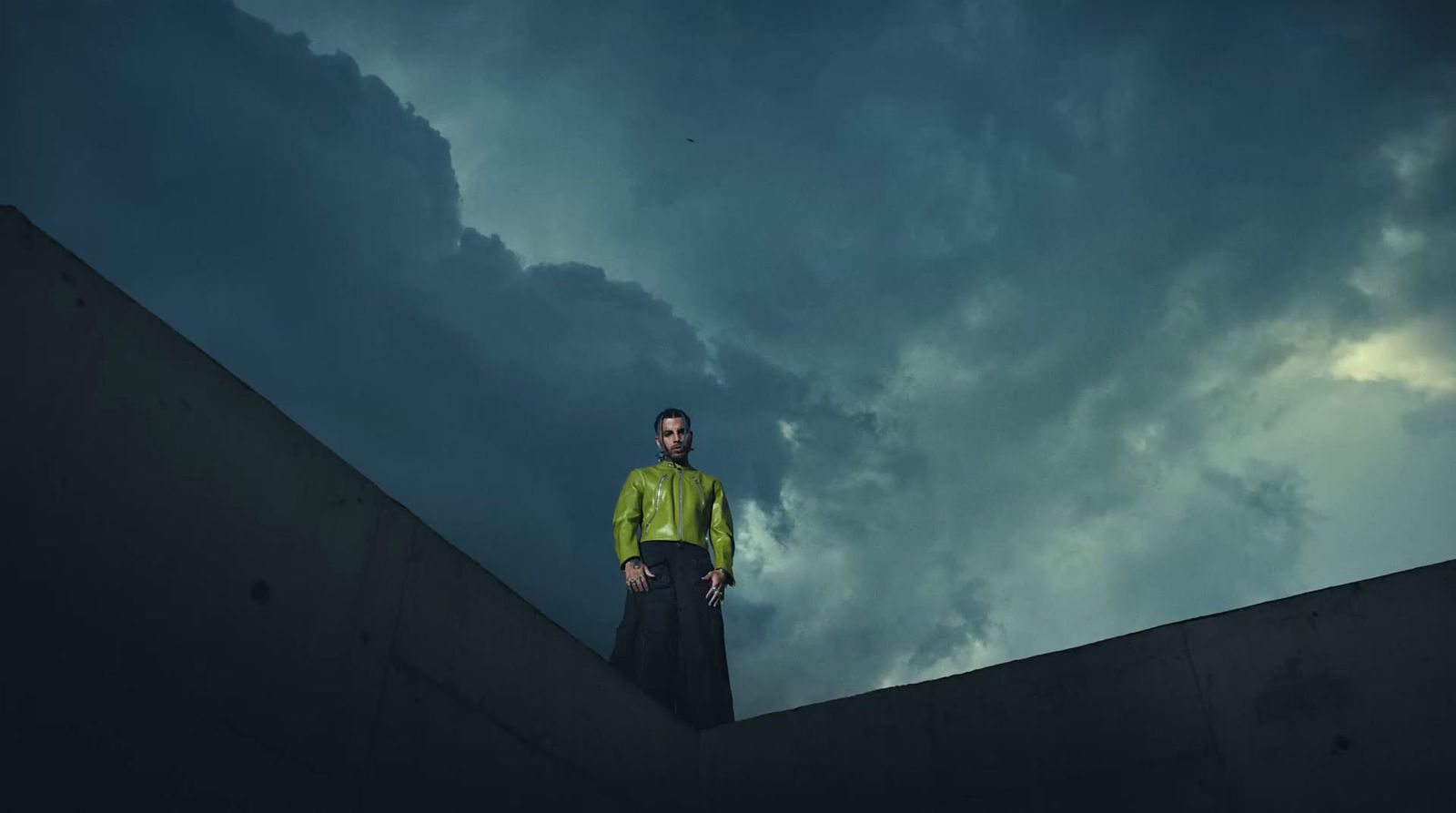 a man standing on a ledge under a cloudy sky