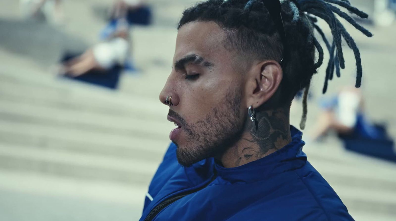 a man with dreadlocks standing in front of a stadium