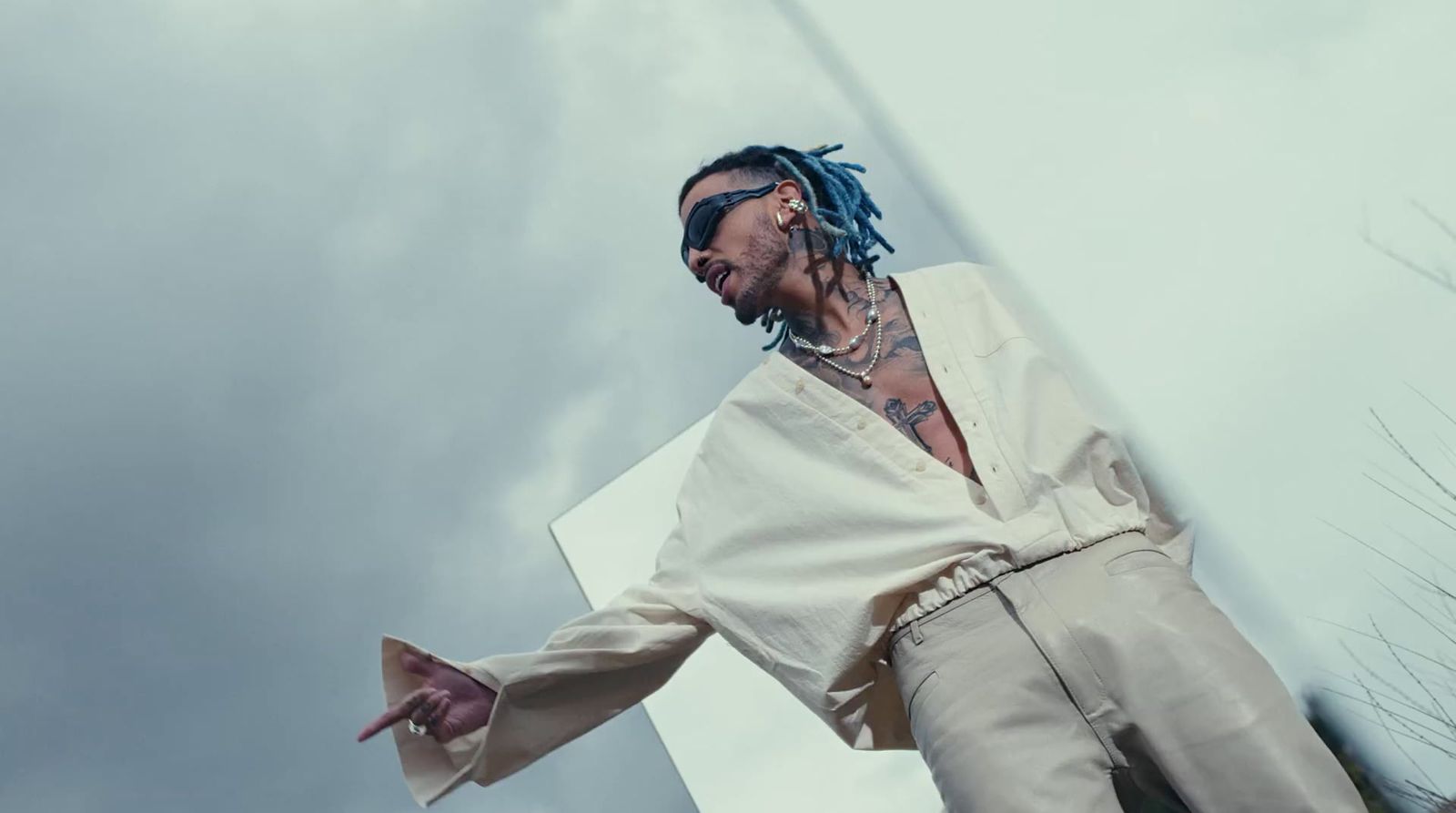 a man with dreadlocks standing in front of a tall building