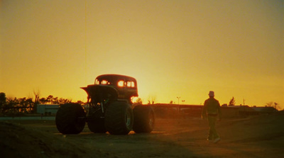 a man standing next to a tractor on a dirt road