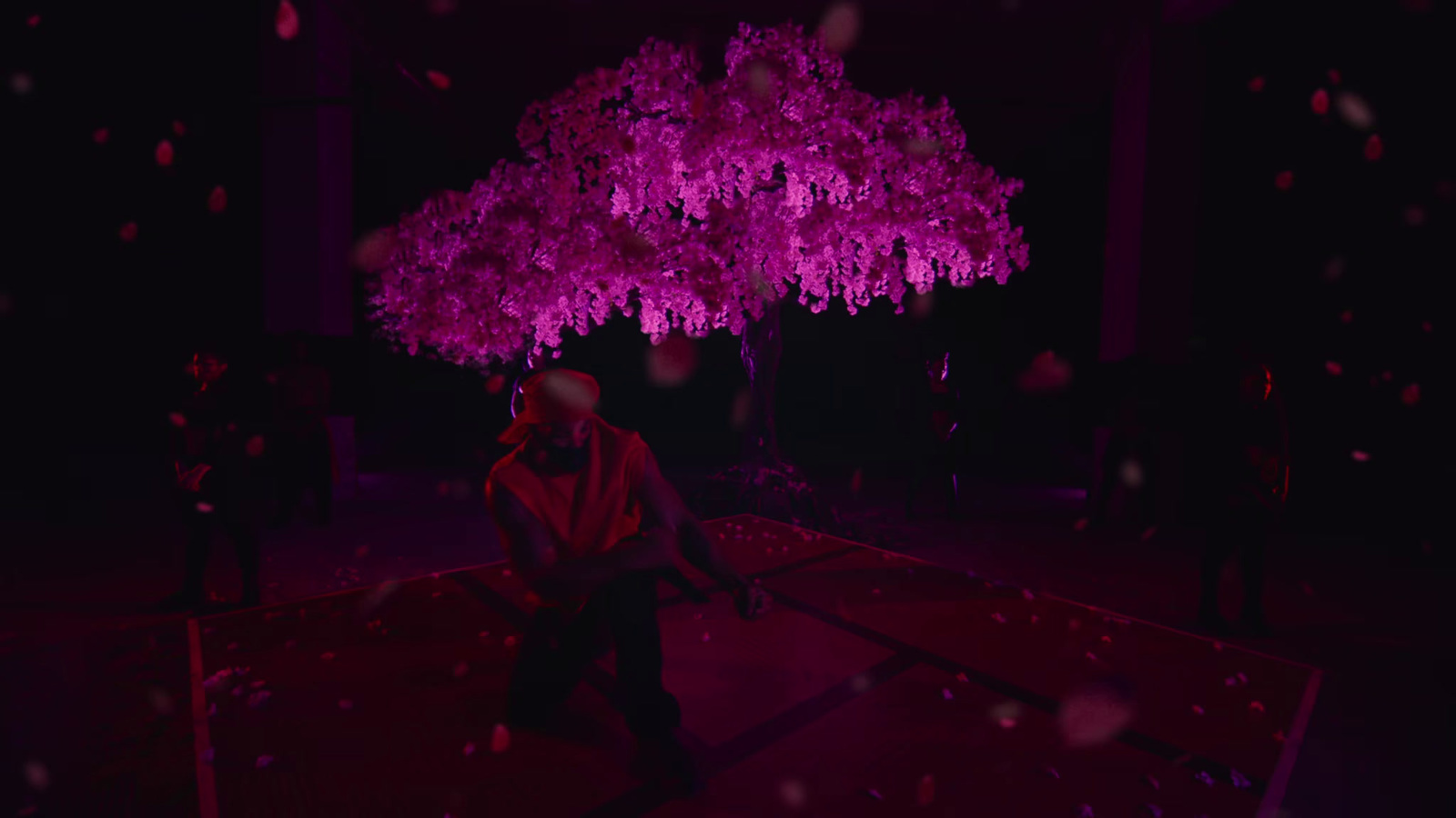 a man sitting under a purple tree in the dark