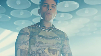 a man with blue hair wearing a shirt with a chain around his neck