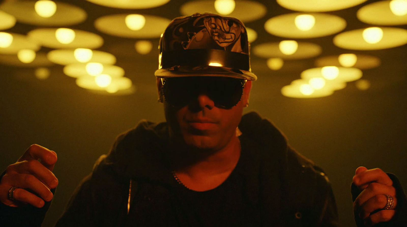 a man wearing a hat and sunglasses in a dark room