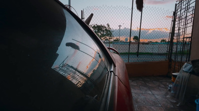 a red car parked next to a tall fence