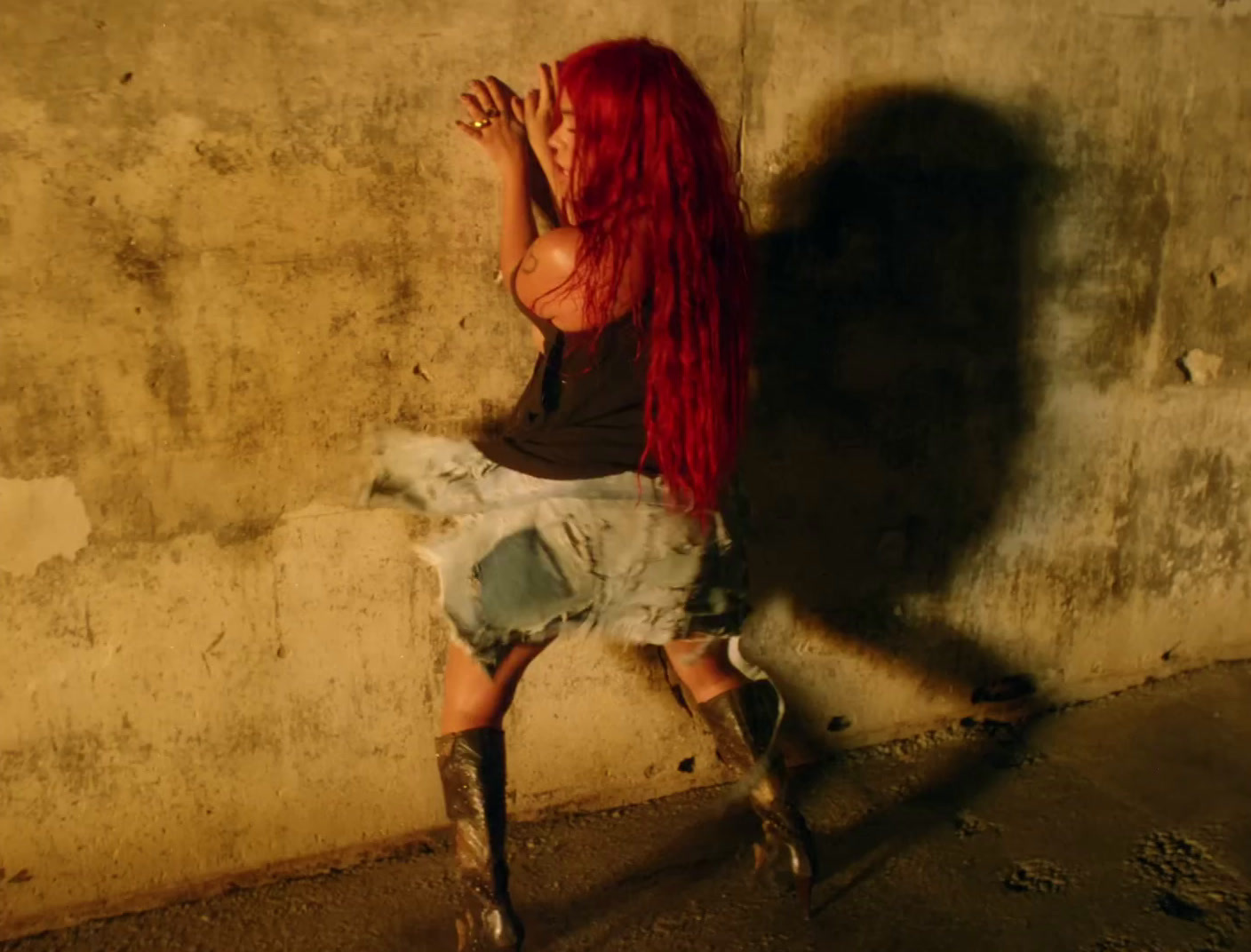 a woman with long red hair leaning against a wall