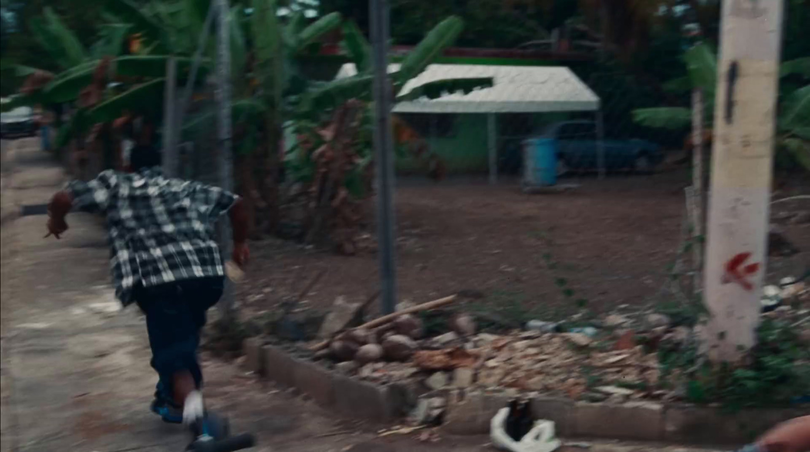 a man walking down a street next to palm trees