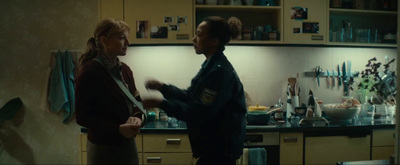 two people standing in a kitchen talking to each other