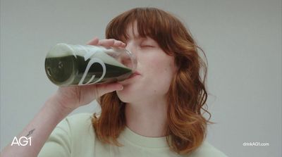 a woman drinking a glass of green liquid