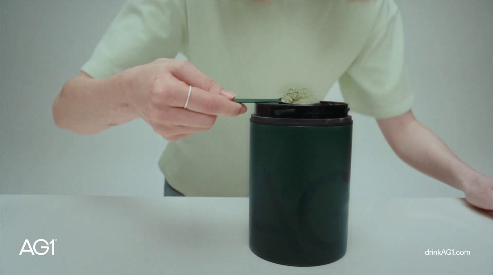 a woman putting something in a green cup