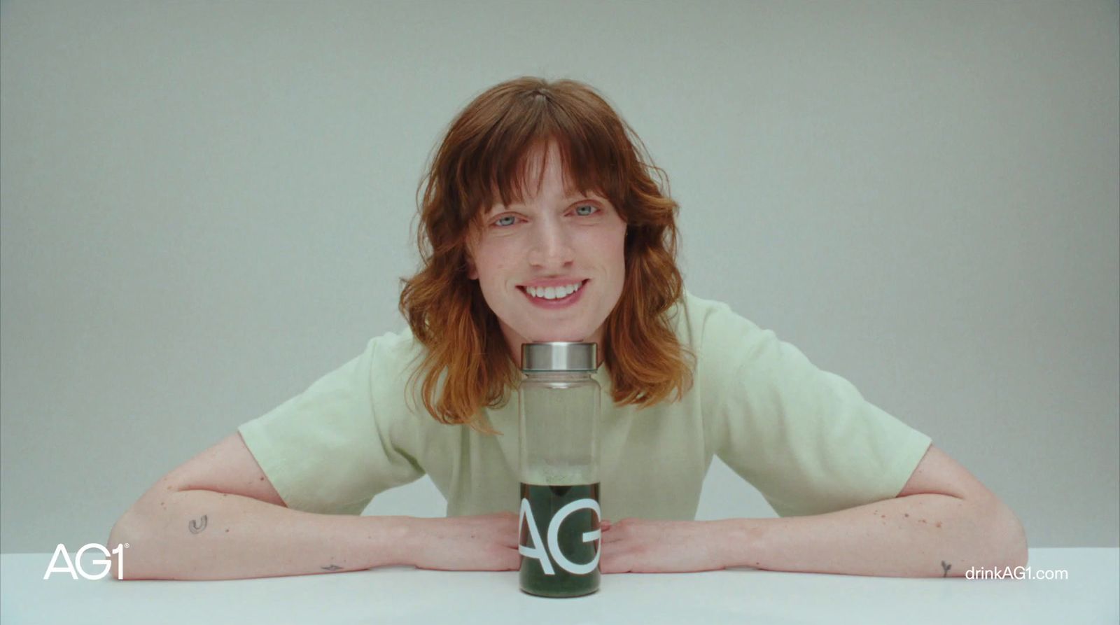 a woman sitting at a table with a bottle in front of her