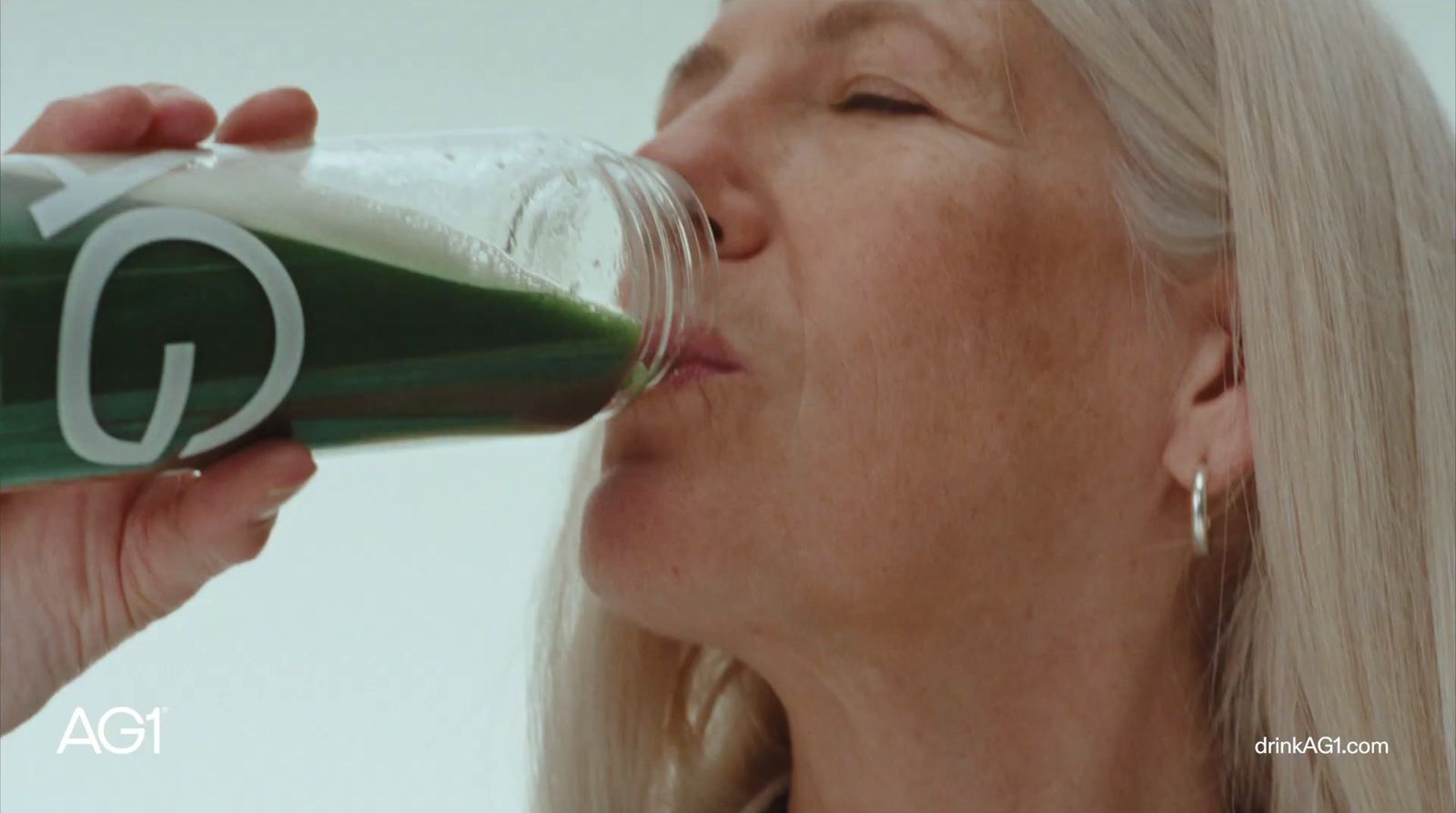 a woman drinking a glass of green juice