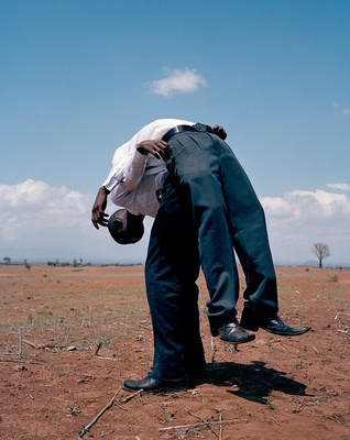 a man bending over in the middle of a field