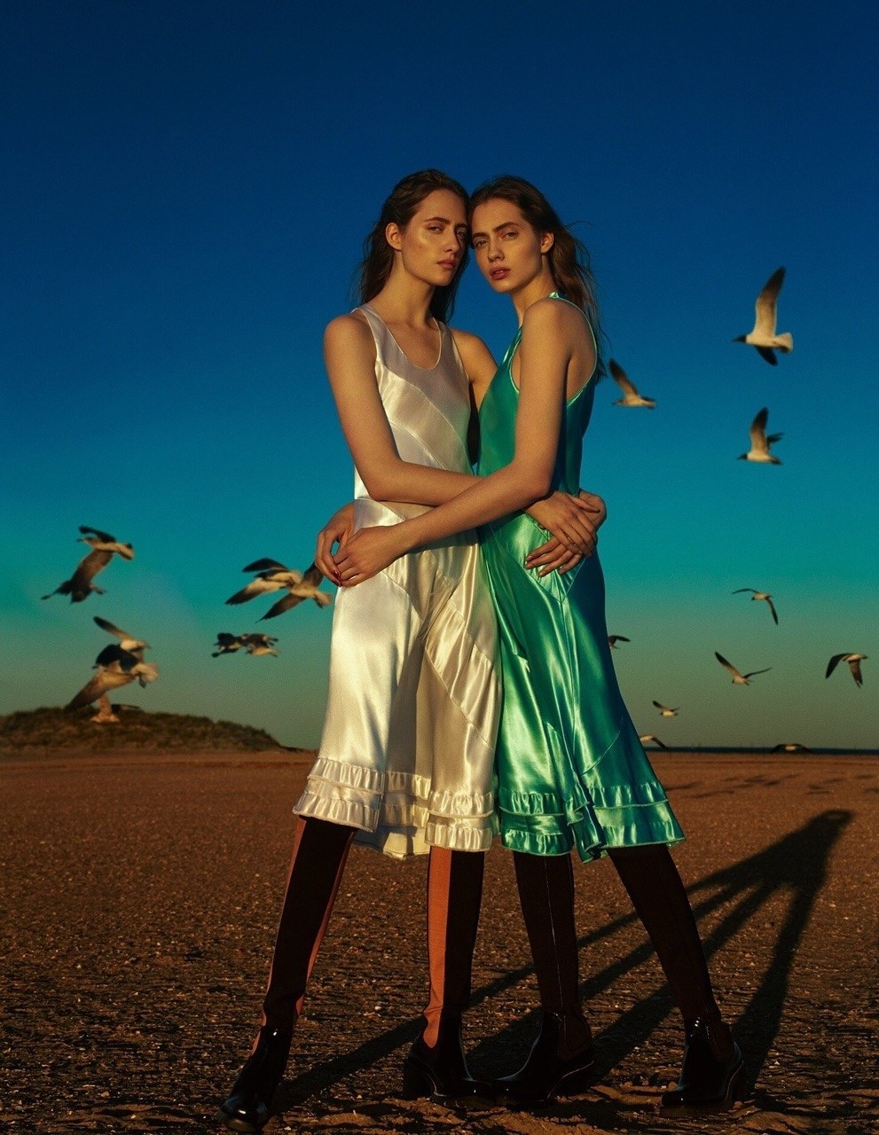 two women standing next to each other on a beach