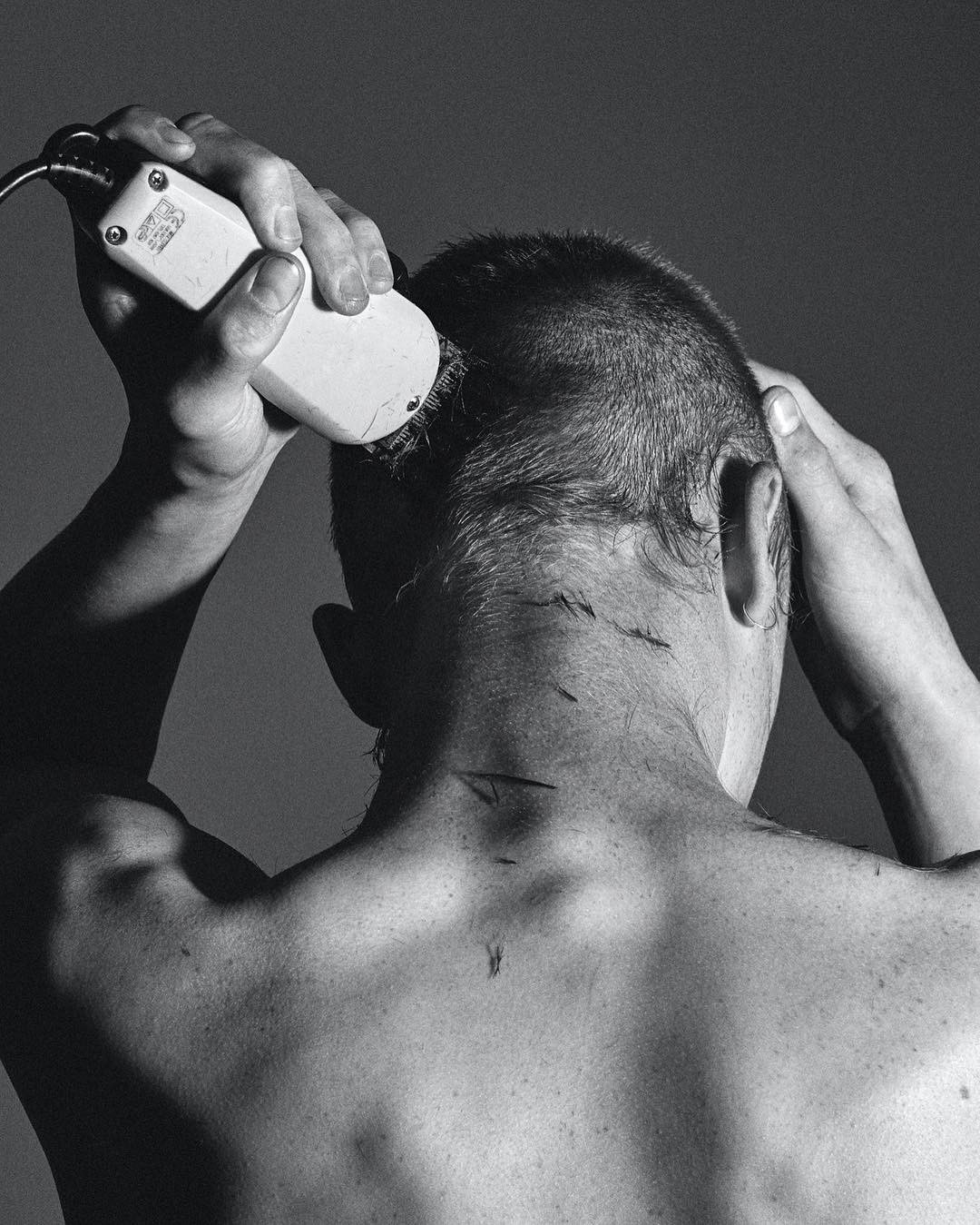 a shirtless man holding a cell phone to his ear