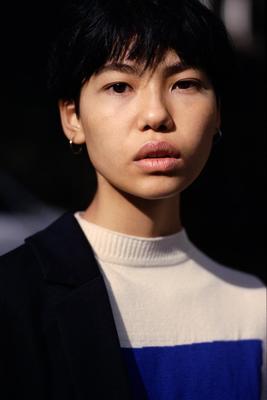 a woman with black hair and a blue and white shirt