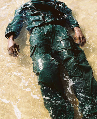 a man laying in the water wearing a green suit