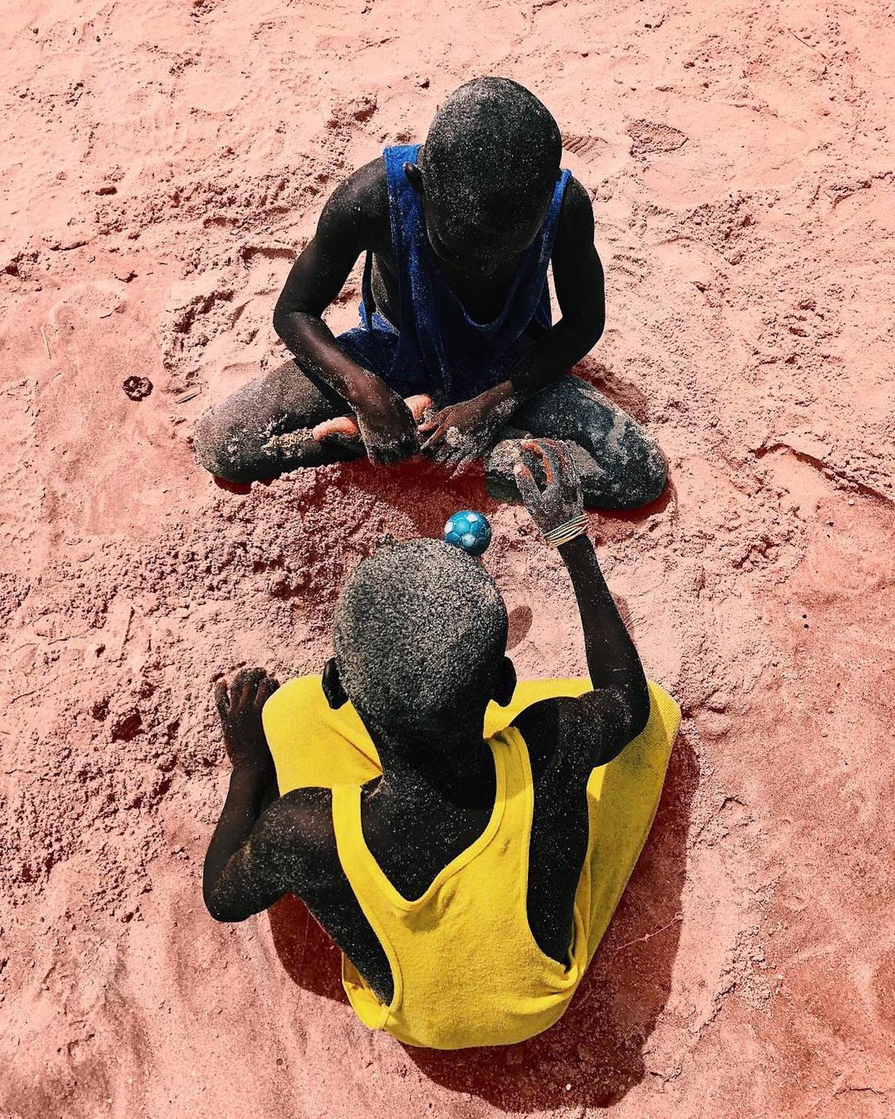 a couple of men sitting on top of a sandy beach