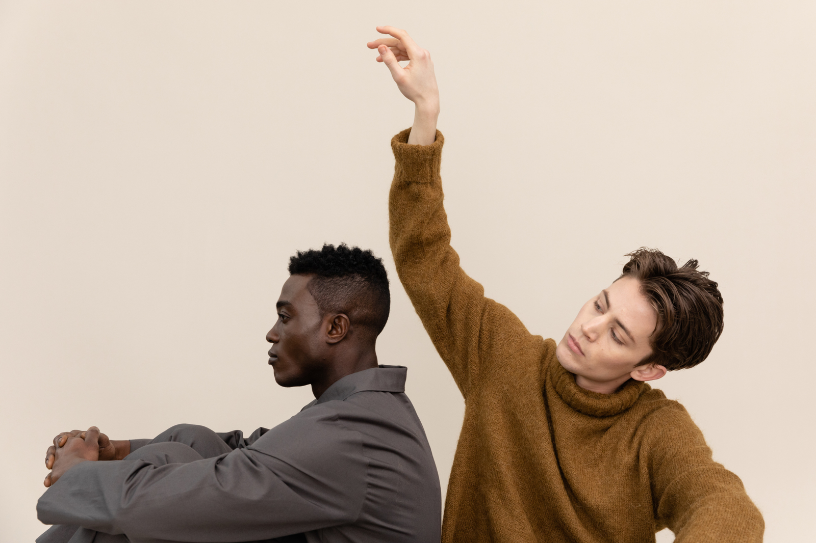 two men sitting down and one is raising his hand