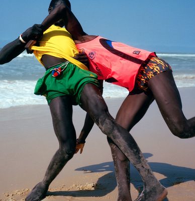 a couple of men playing a game of frisbee on the beach