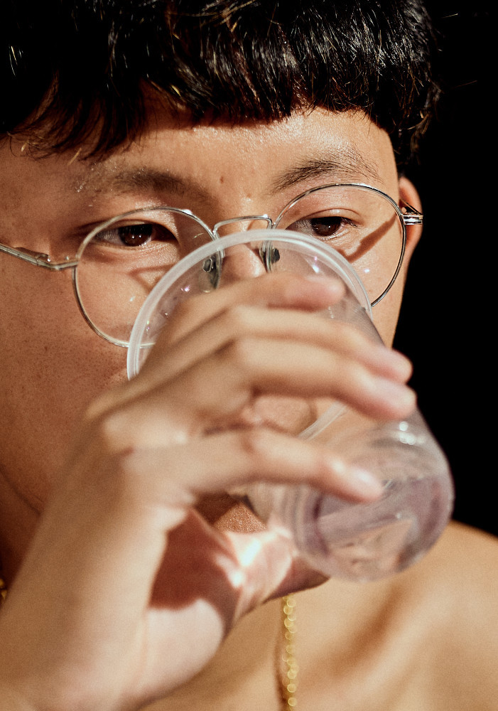 a man wearing glasses drinking from a plastic cup