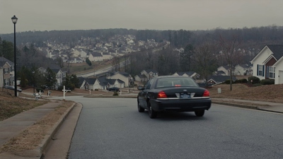 a black car driving down a street next to houses