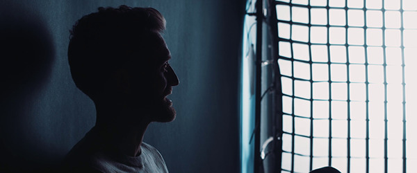 a man standing next to a window in a dark room