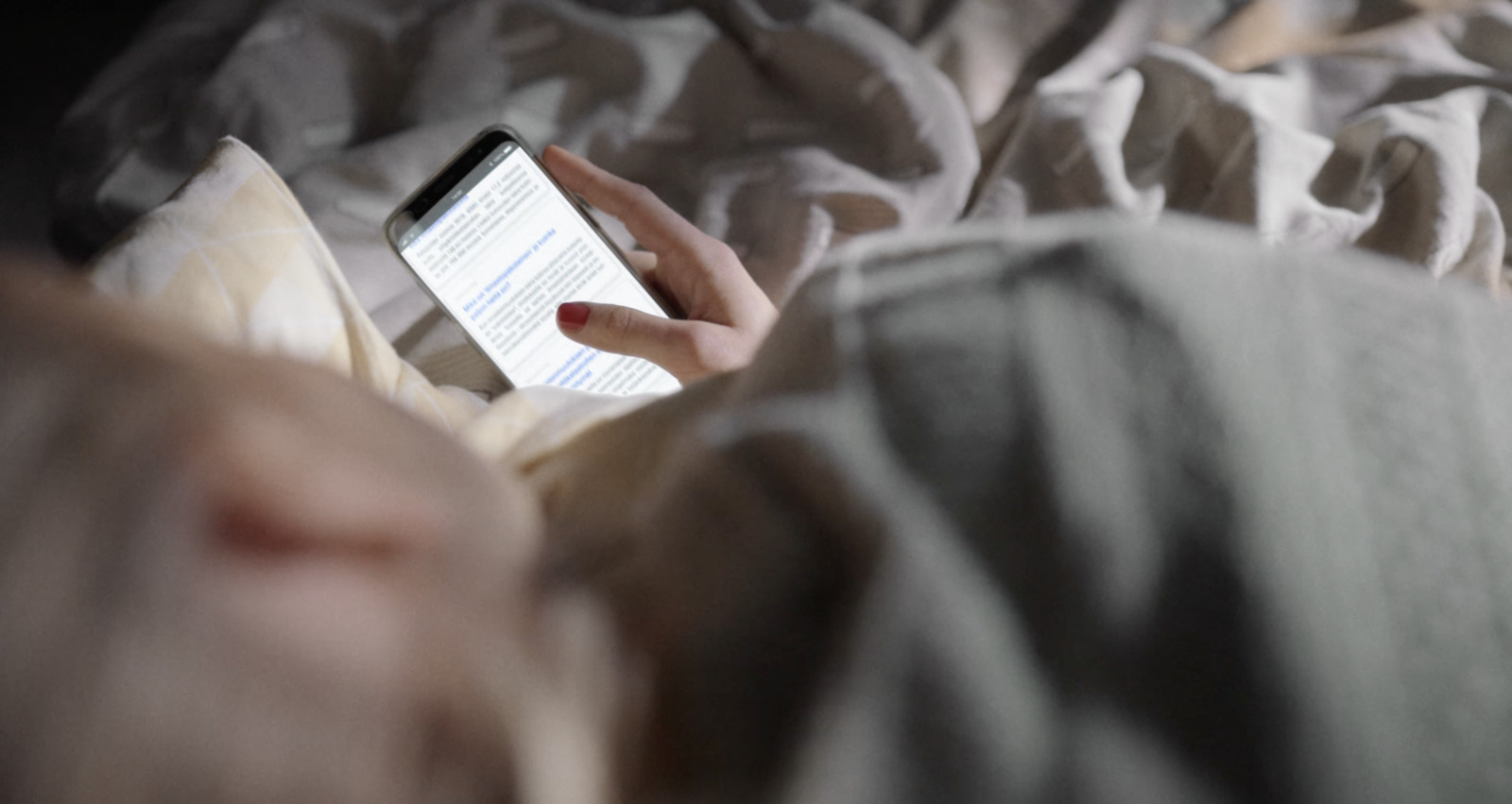 a person laying in bed with a cell phone