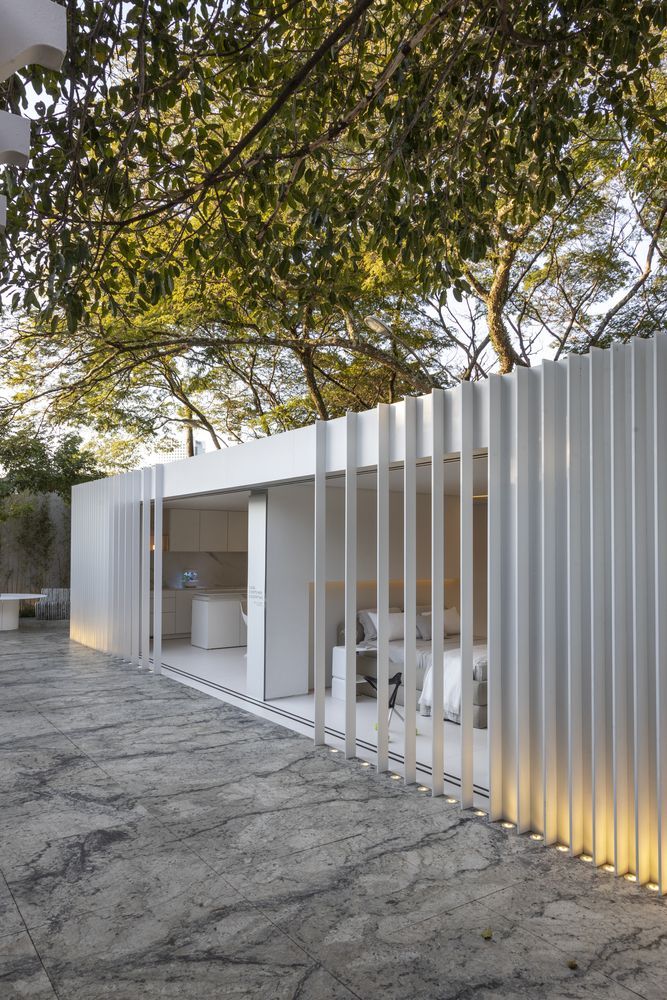 a white building with a white wall and trees in the background