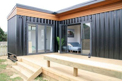 a house made out of shipping containers sitting on top of a wooden deck