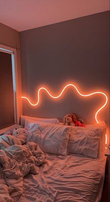 a bed with a white comforter and a neon headboard