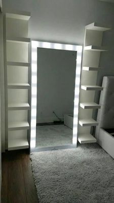 a room with a mirror, shelves, and a bed