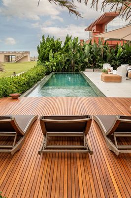 two lawn chairs sitting on top of a wooden deck next to a swimming pool