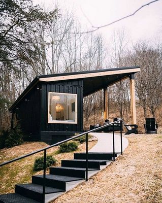 a black cabin with stairs leading up to it