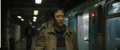 a man walking down a train station next to a window