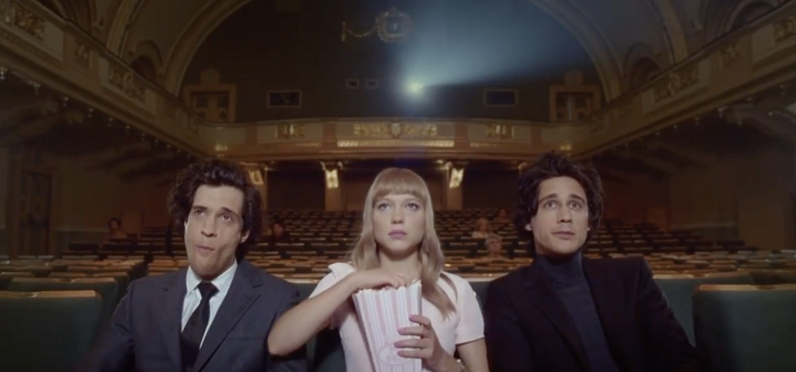 two men and a woman sitting in a theater